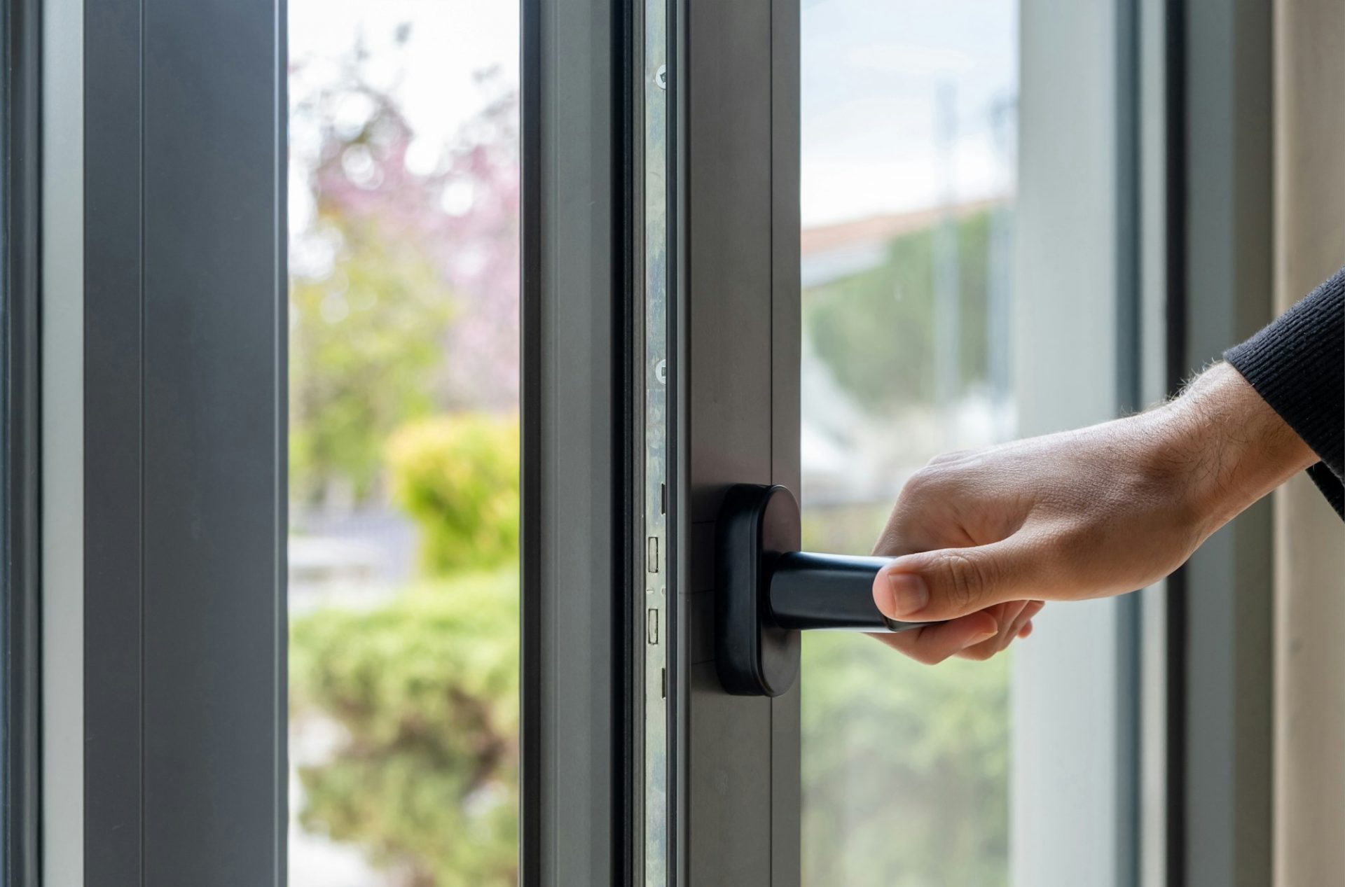 Aluminum window frame detail. Male hand opens the metal door closeup view.